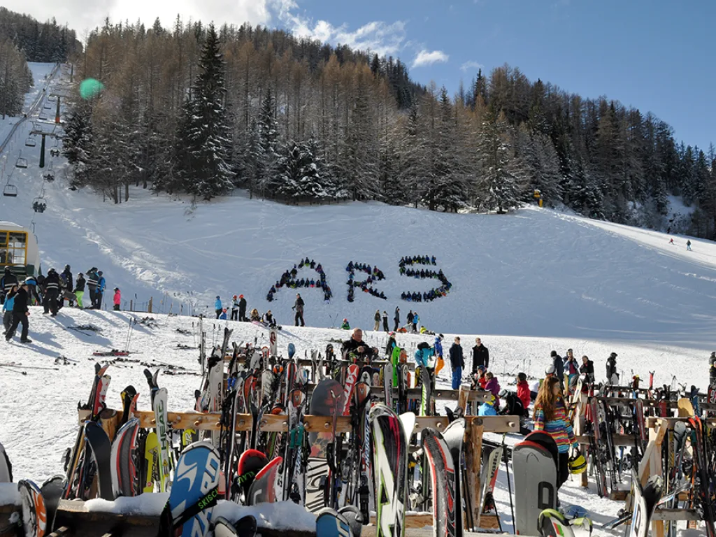 Der Schriftzug ARS am Hang, davor abgestellte Ski und Snowboards.